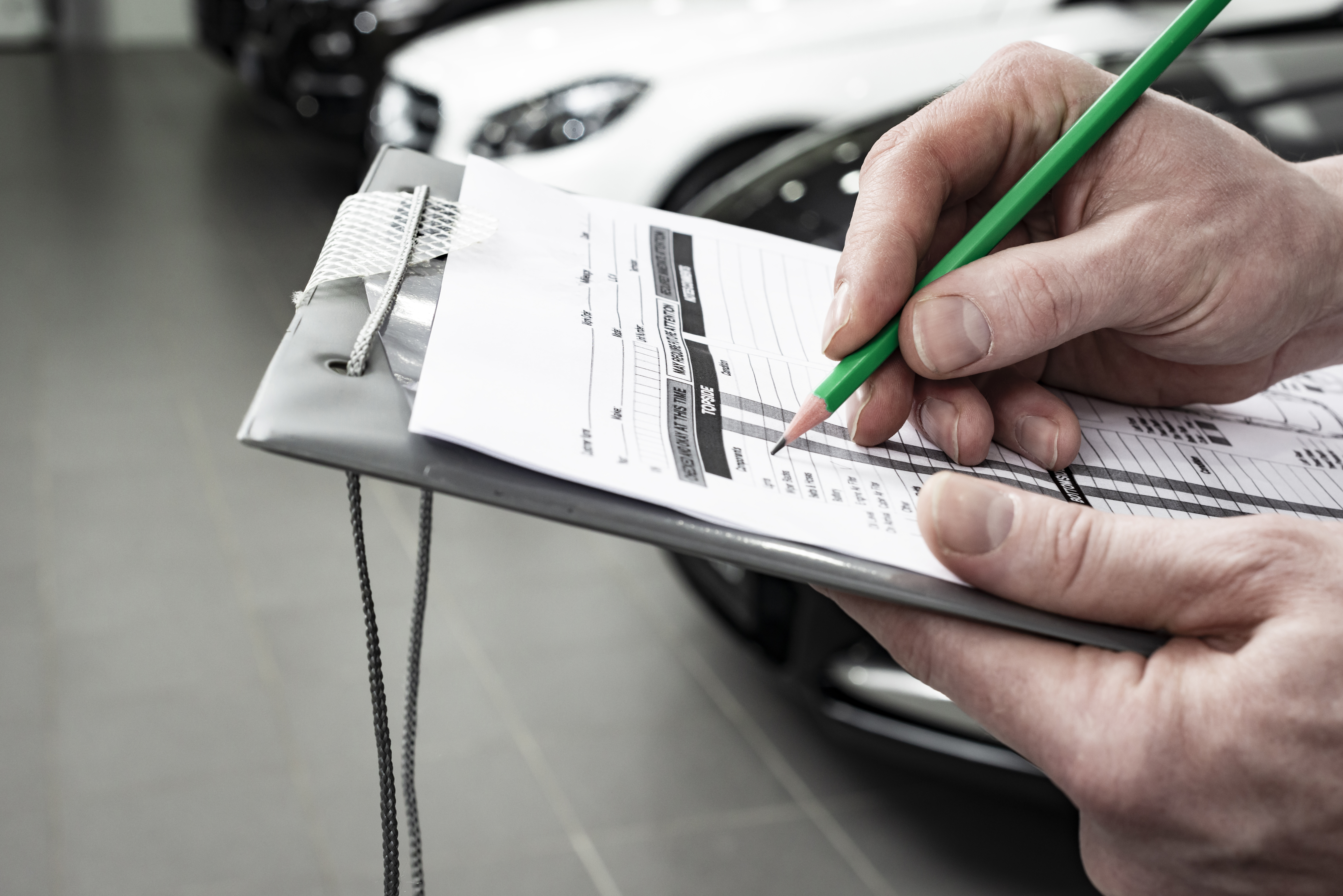 Ein Mann geht anhand einer Checkliste wichtige Punkte zum Autoverkauf durch.