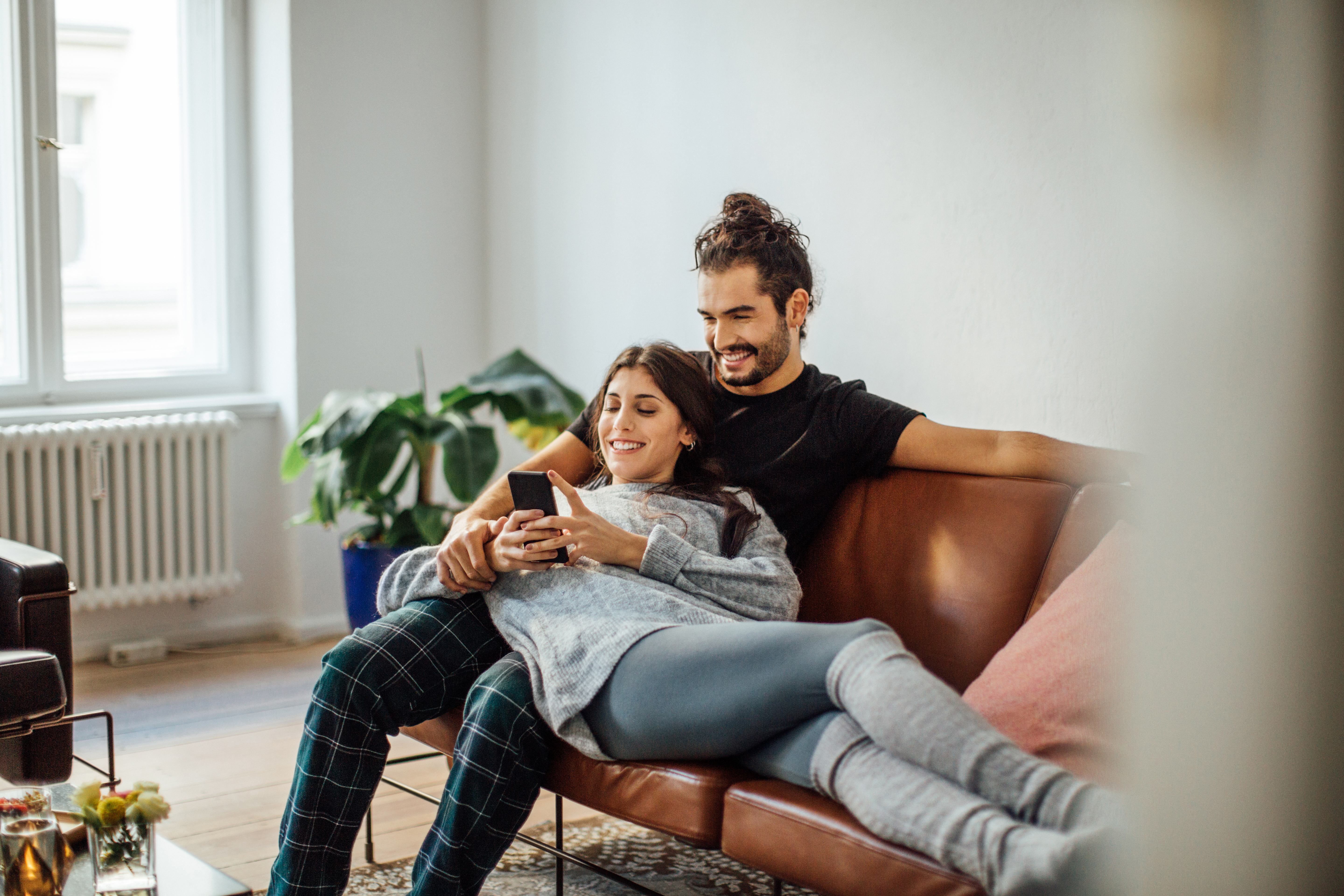 Sie inserieren, wir erledigen den Rest Ein glückliches Paar sitzt auf dem Sofa und inseriert sein Auto bequem online.