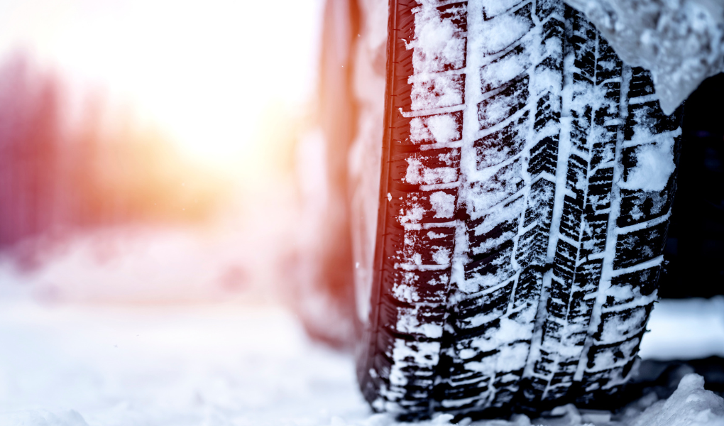Ein Reifen steht auf einer verschneiten Straße und symbolisiert die Frage nach der Winterreifenpflicht für Anhänger. 
