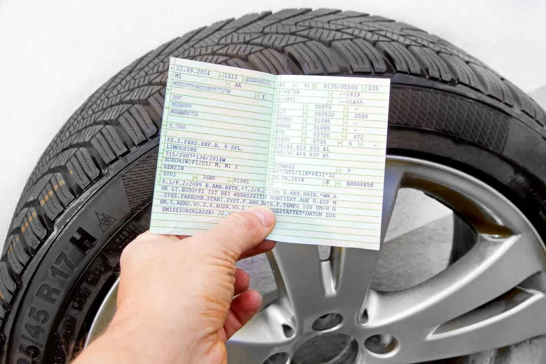 Die Grafik zeigt eine Hand vor einem Reifen die einen Fahrzeugschein mit Reifenbezeichnung hält.